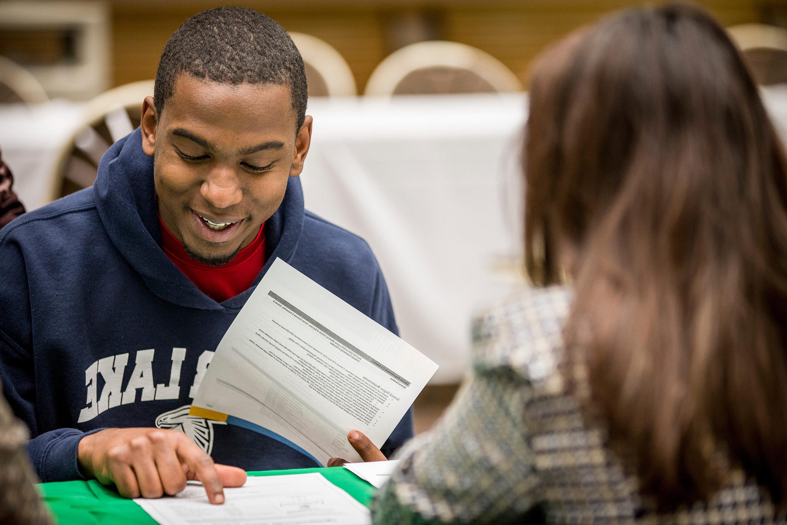 Student smiling 和 reading through papers